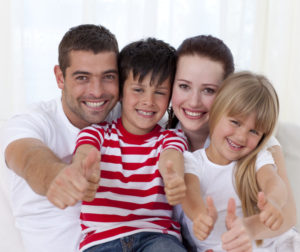 Family Sitting On Sofa With Thumbs Up